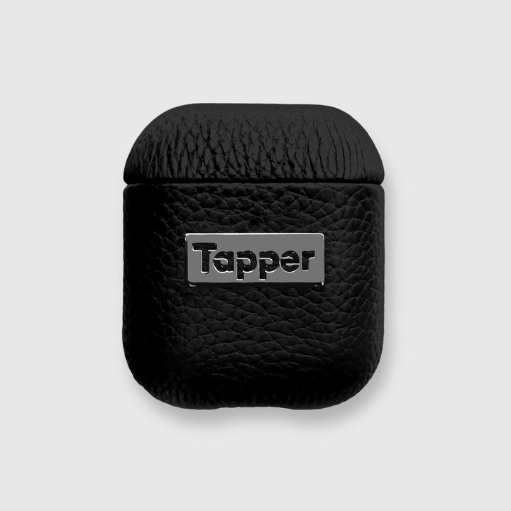 Tapper's luxurious black genuine lamb leather AirPods case protects and elevates the look of your AirPods. The luxurious, protective case for AirPods with a metal logo plate in hematite black plating steps up your AirPods game. The next must-have high end protective Apple AirPods accessory in real leather and precious metals. Compatible with AirPods (1st and 2nd generation). Designed in Sweden by Tapper. Free Express Shipping at gettapper.com