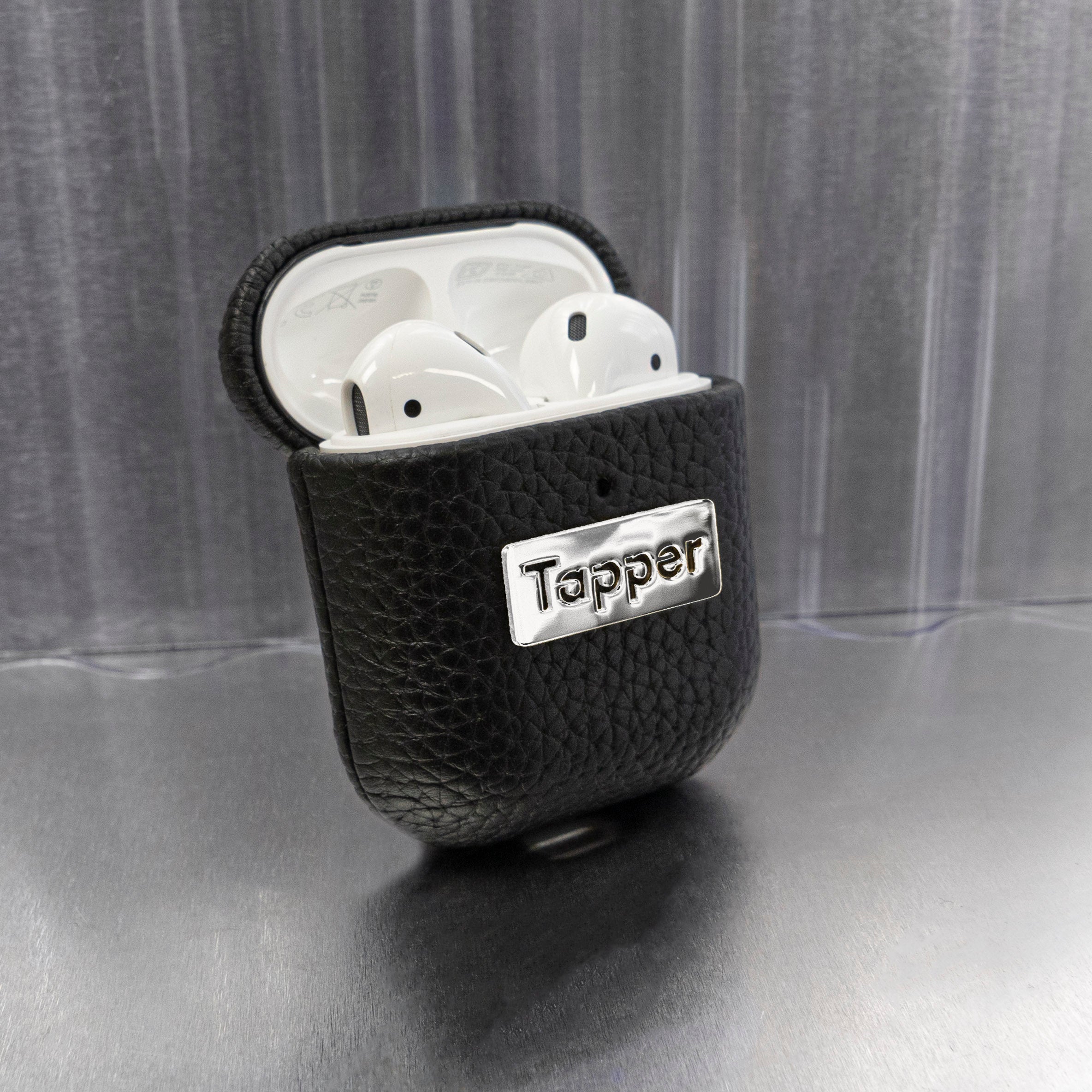 Tapper's luxurious black genuine cow leather AirPods case protects and elevates the look of your AirPods. The luxurious, protective case for AirPods with a metal logo plate colored in silver steps up your AirPods game. The next must-have high end protective Apple AirPods accessory in real leather and metal details. Compatible with AirPods (1st and 2nd generation). Designed in Sweden by Tapper. Free Express Shipping at gettapper.com