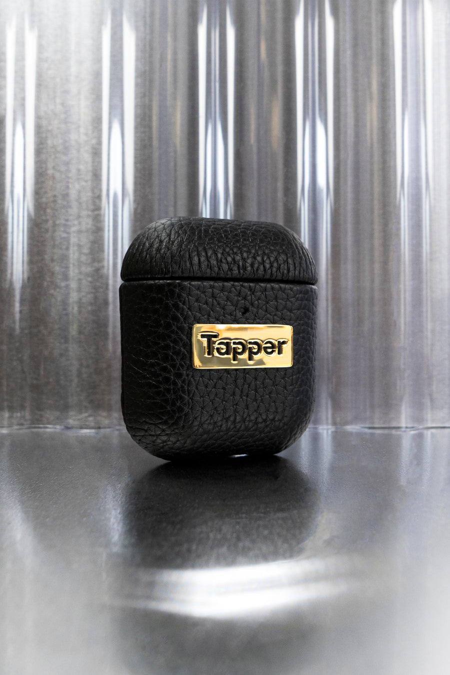Tapper's luxurious black genuine cow leather AirPods case protects and elevates the look of your AirPods. The luxurious, protective case for AirPods with a metal logo plate in real 18k gold plating steps up your AirPods game. The next must-have high end protective Apple AirPods accessory in real leather and precious metals. Compatible with AirPods (1st and 2nd generation). Designed in Sweden by Tapper. Free Express Shipping at gettapper.com