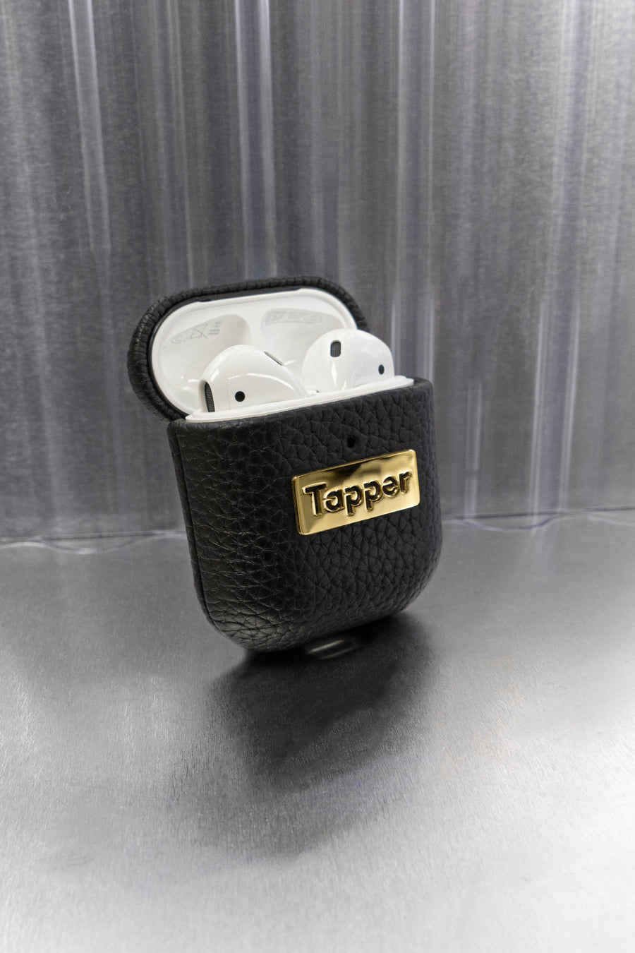 Tapper's luxurious black genuine cow leather AirPods case protects and elevates the look of your AirPods. The luxurious, protective case for AirPods with a metal logo plate in real 18k gold plating steps up your AirPods game. The next must-have high end protective Apple AirPods accessory in real leather and precious metals. Compatible with AirPods (1st and 2nd generation). Designed in Sweden by Tapper. Free Express Shipping at gettapper.com