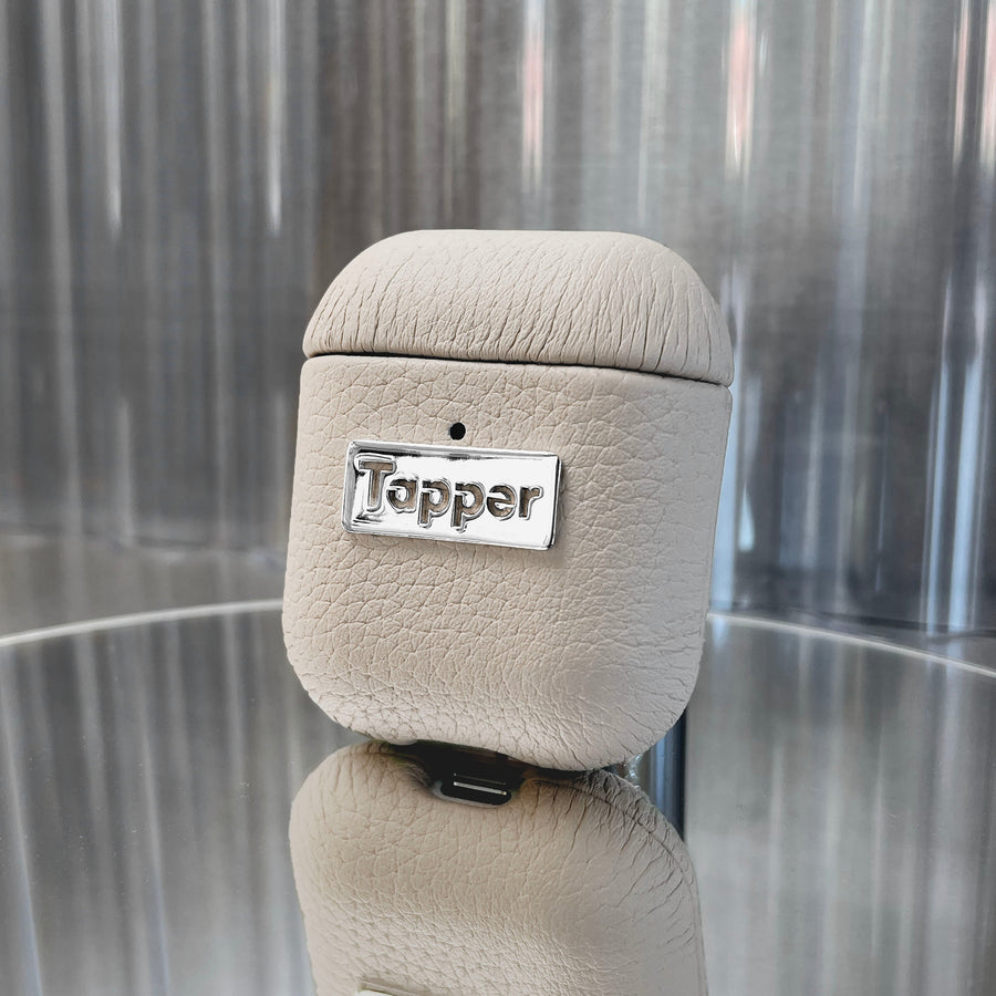 Tapper's luxurious sand beige genuine cow leather AirPods case protects and elevates the look of your AirPods. The luxurious, protective case for AirPods with a metal logo plate colored in silver steps up your AirPods game. The next must-have high end protective Apple AirPods accessory in real leather and metal details. Compatible with AirPods (1st and 2nd generation). Designed in Sweden by Tapper. Free Express Shipping at gettapper.com