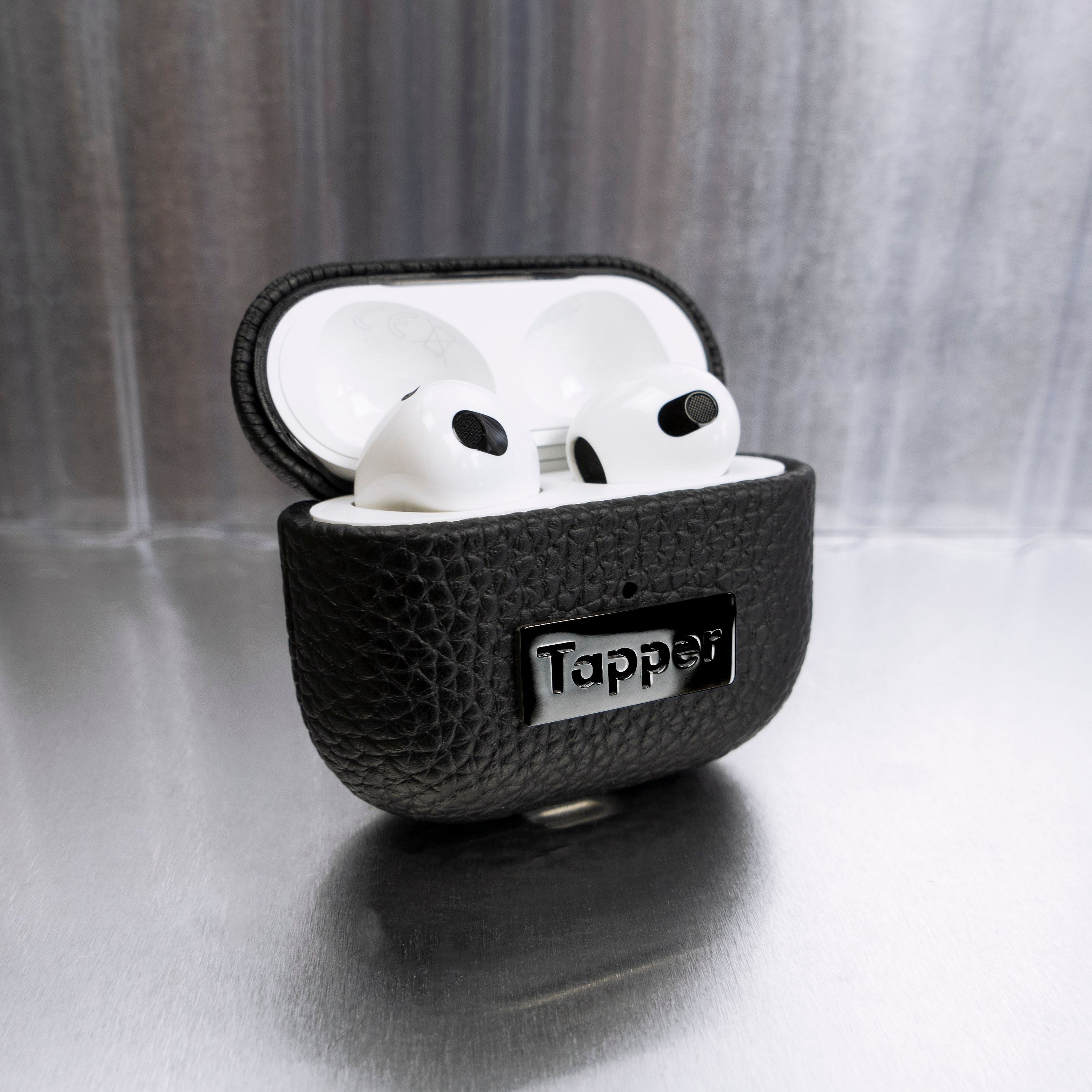 Tapper's luxurious black genuine cow leather AirPods case protects and elevates the look of your AirPods. The luxurious, protective case for AirPods with a metal logo plate in hematite black plating steps up your AirPods game. The next must-have high end protective Apple AirPods accessory in real leather and precious metals. Compatible with AirPods (3rd generation). Designed in Sweden by Tapper. Free Express Shipping at gettapper.com