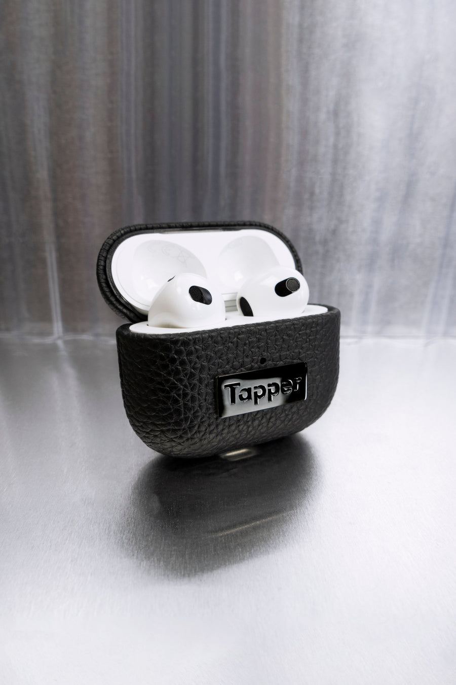 Tapper's luxurious black genuine cow leather AirPods case protects and elevates the look of your AirPods. The luxurious, protective case for AirPods with a metal logo plate in hematite black plating steps up your AirPods game. The next must-have high end protective Apple AirPods accessory in real leather and precious metals. Compatible with AirPods (3rd generation). Designed in Sweden by Tapper. Free Express Shipping at gettapper.com