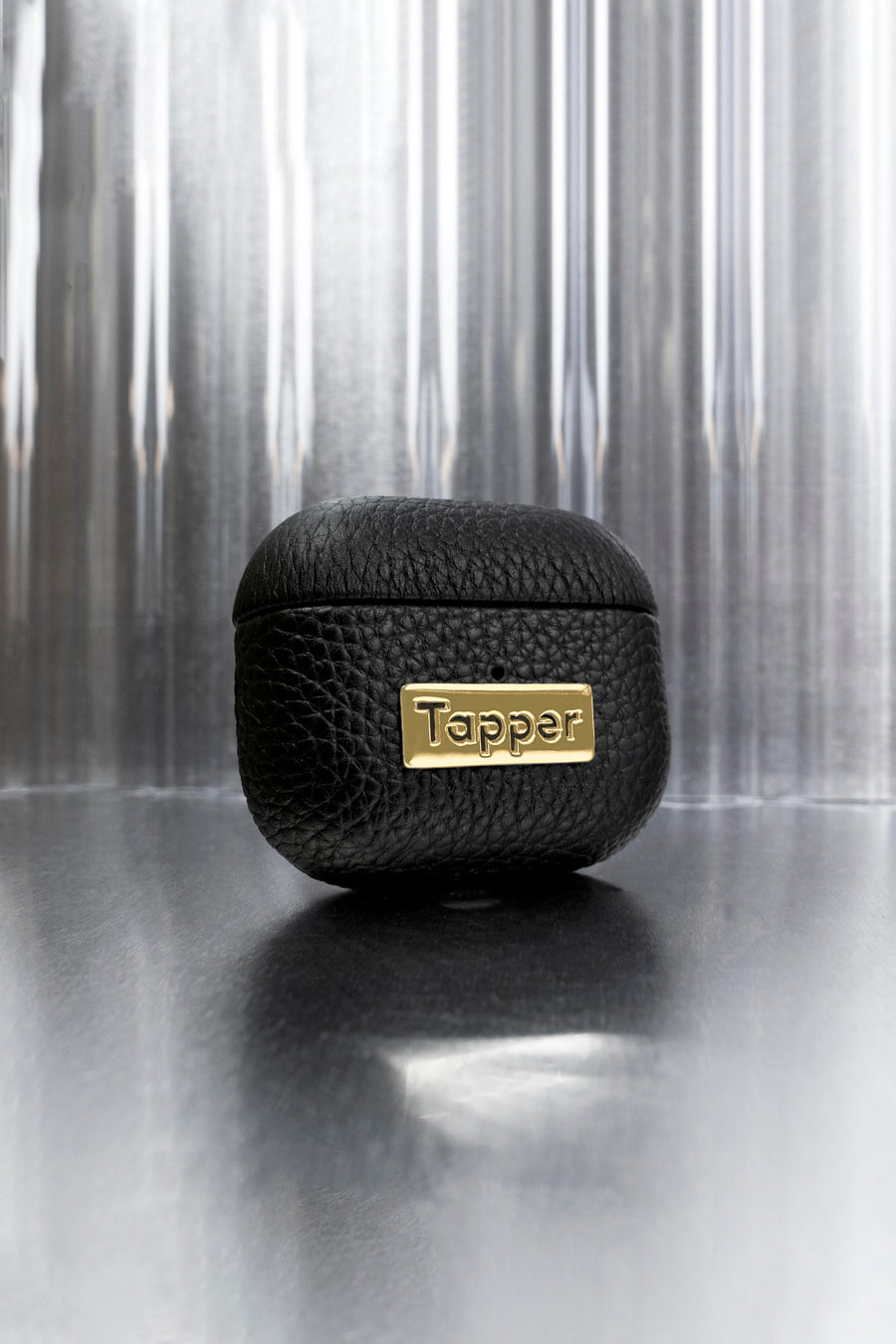 Tapper's luxurious black genuine cow leather AirPods case protects and elevates the look of your AirPods. The luxurious, protective case for AirPods with a metal logo plate in real 18k gold plating steps up your AirPods game. The next must-have high end protective Apple AirPods accessory in real leather and precious metals. Compatible with AirPods (3rd generation). Designed in Sweden by Tapper. Free Express Shipping at gettapper.com